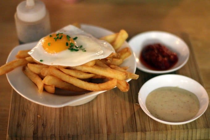 a plate of french fries topped with a fried egg