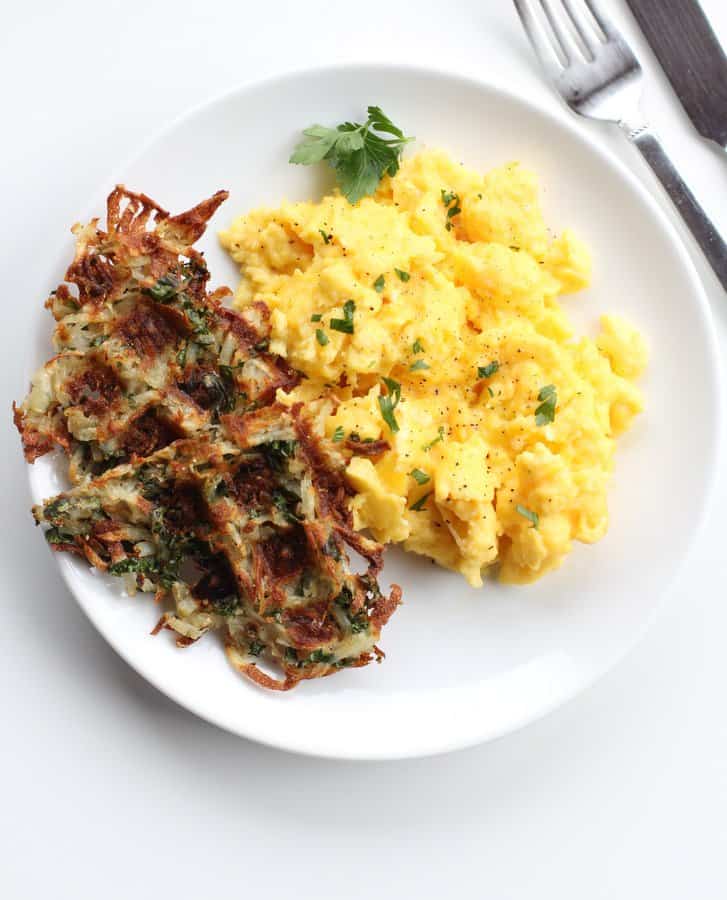 Parmesan Kale Hash Brown Waffles on a white plate with scrambled eggs