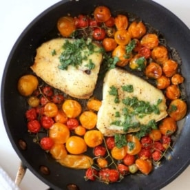 slow roasted halibut in a skillet with cherry tomatoes