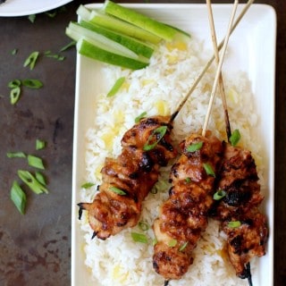 honey garlic glazed chicken skewers on a bed of pineapple rice on a white platter