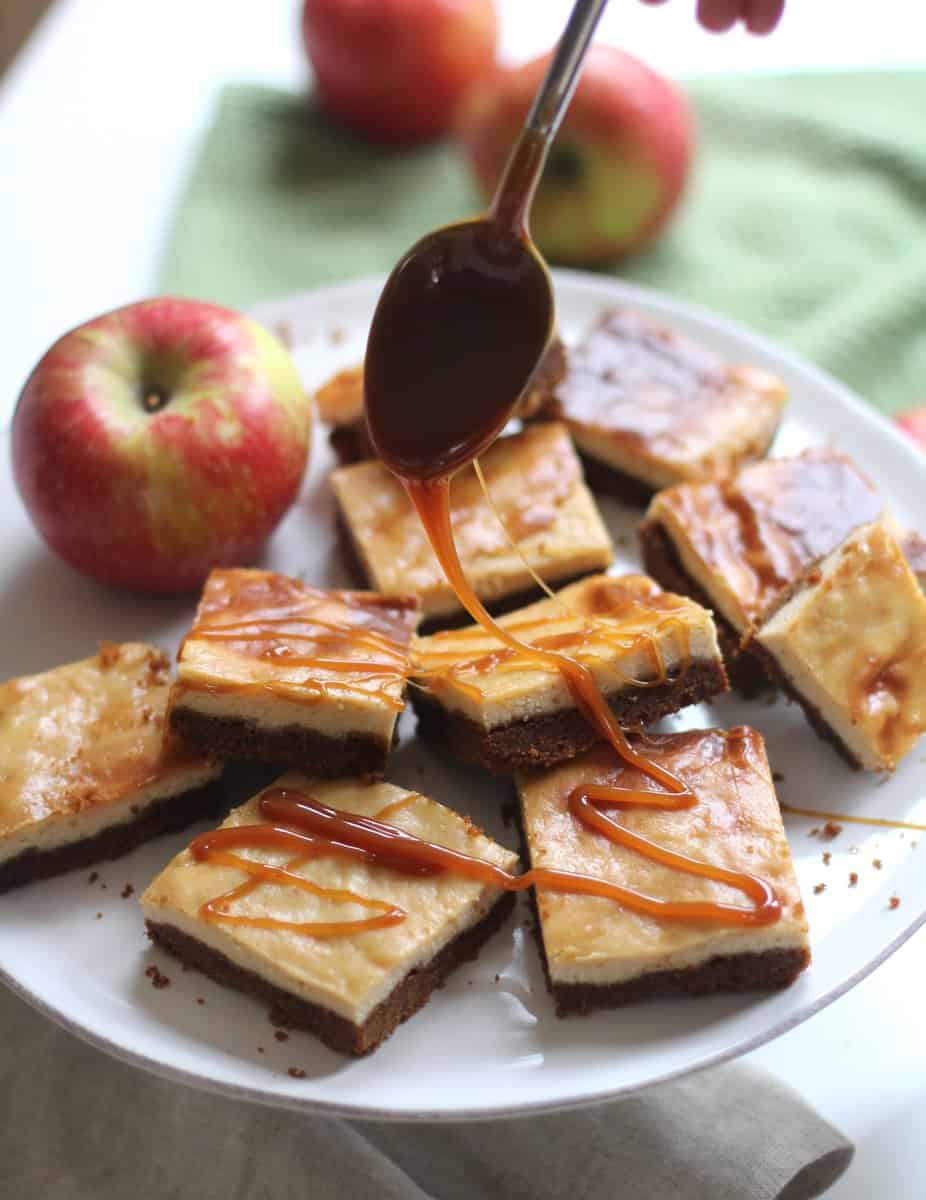 drizzling caramel over apple cider bars on a white plate