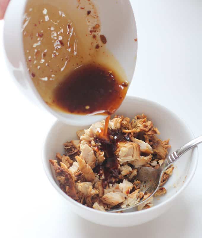 Pouring Sauce over chicken in a white bowl 