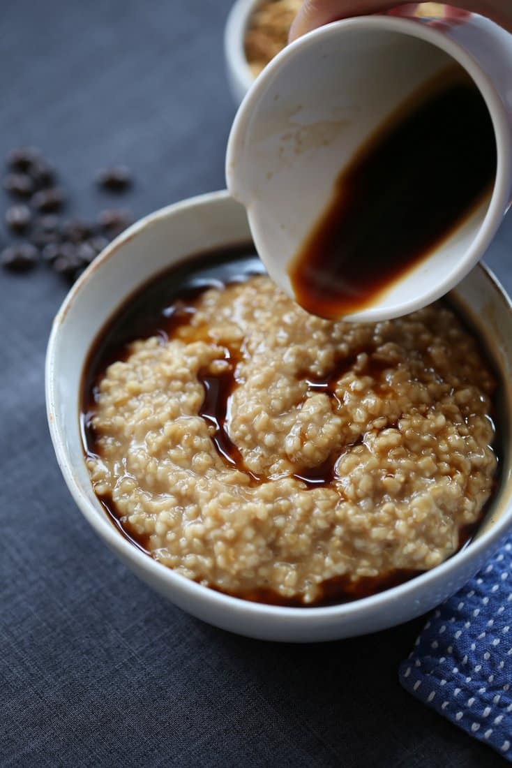 pouring coffee over oats in a white bowl