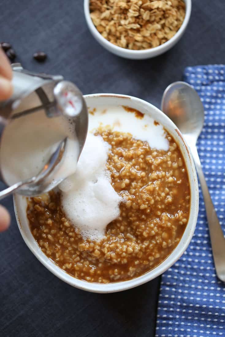 adding cream to the steel cut oats in a white bowl