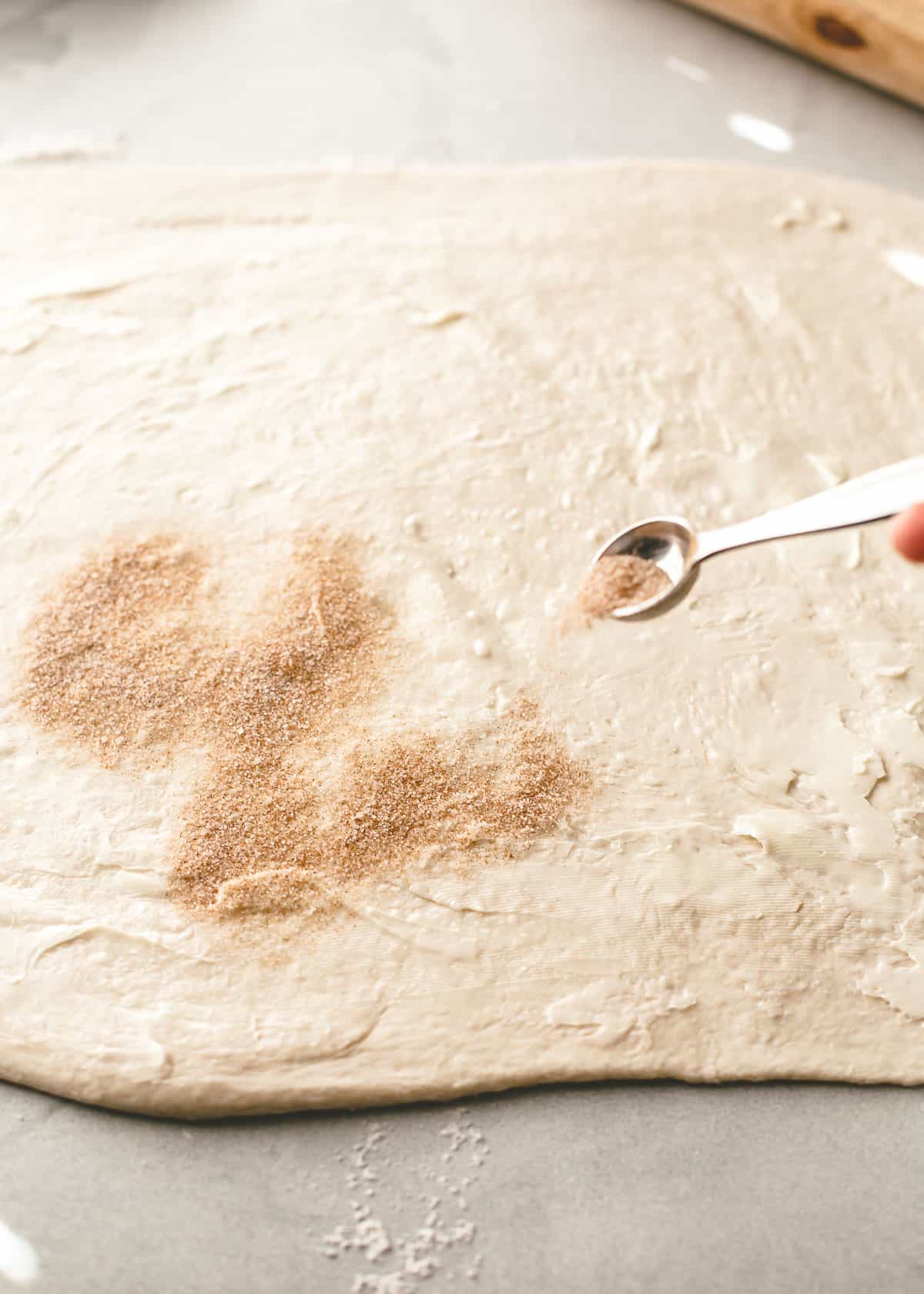 spreading cinnamon onto rolled dough