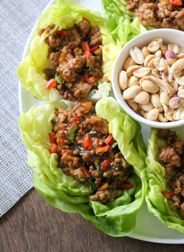  Lettuce Cups on a white plate with a small bowl of peanuts