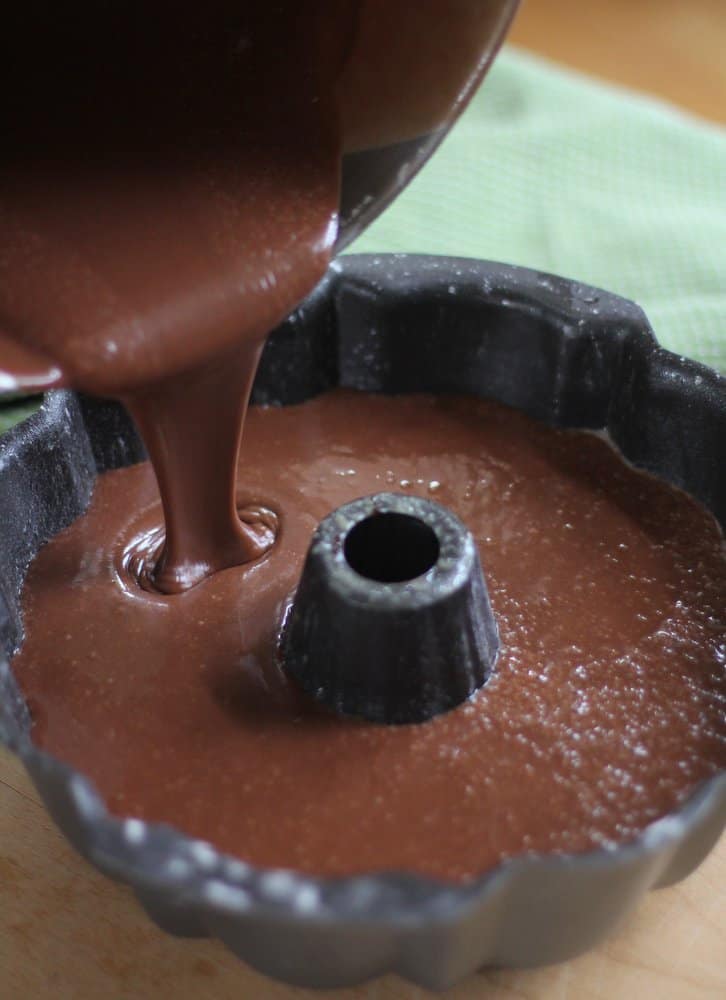 adding chocolate cake mixture to a bundt pan