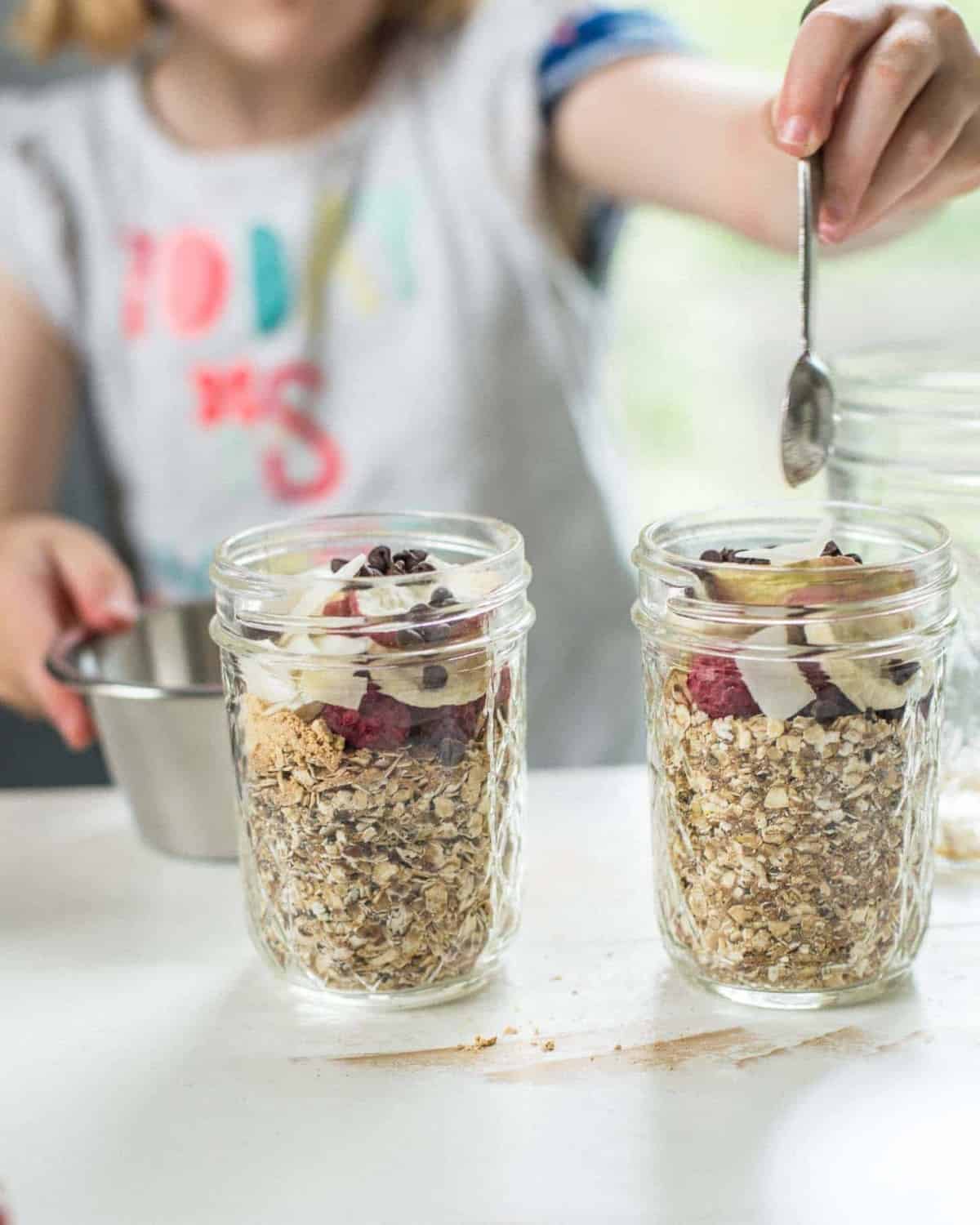 adding toppings to oatmeal in glass jars
