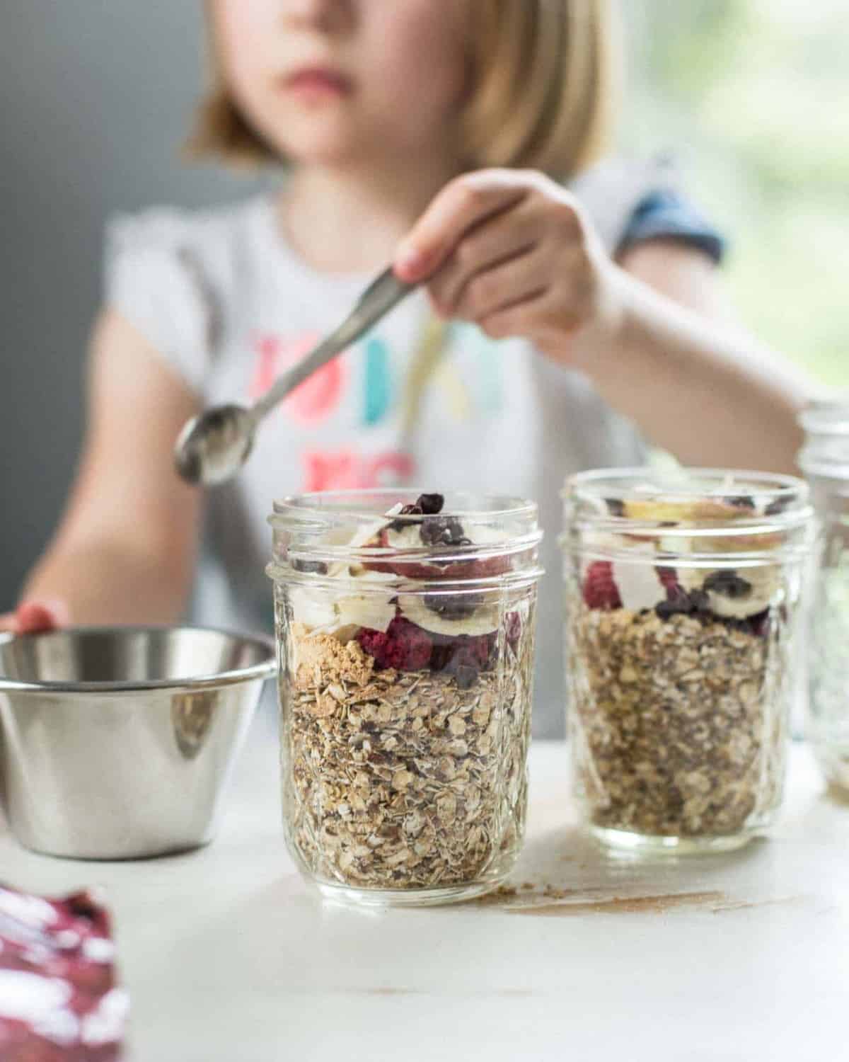 adding toppings to oatmeal in small glass jars