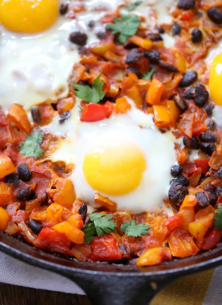 fried eggs over vegetables in a cast iron pan