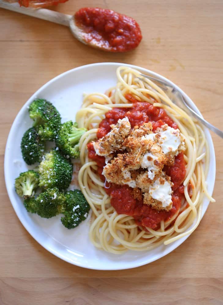 Baked Chicken Parmesan on a white plate with broccoli