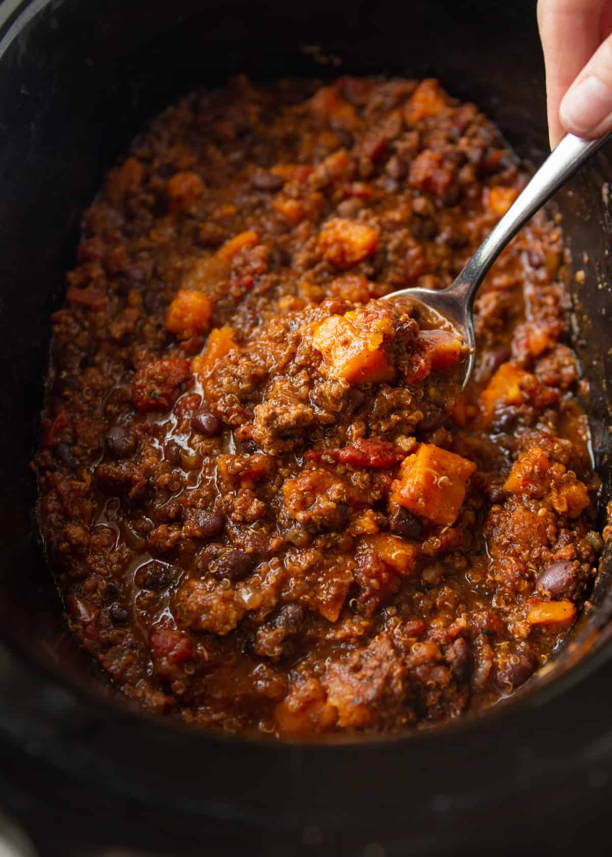 overhead image of chili in the slow cooker being stirred with a spoon