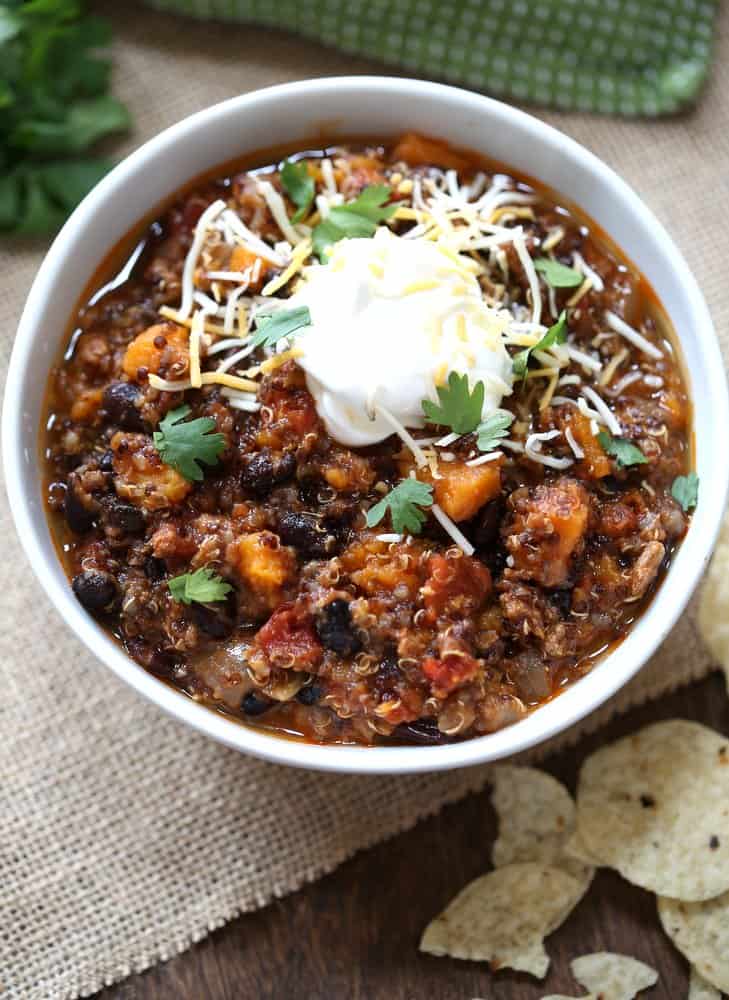 chili in a white bowl topped with sour cream and cheese