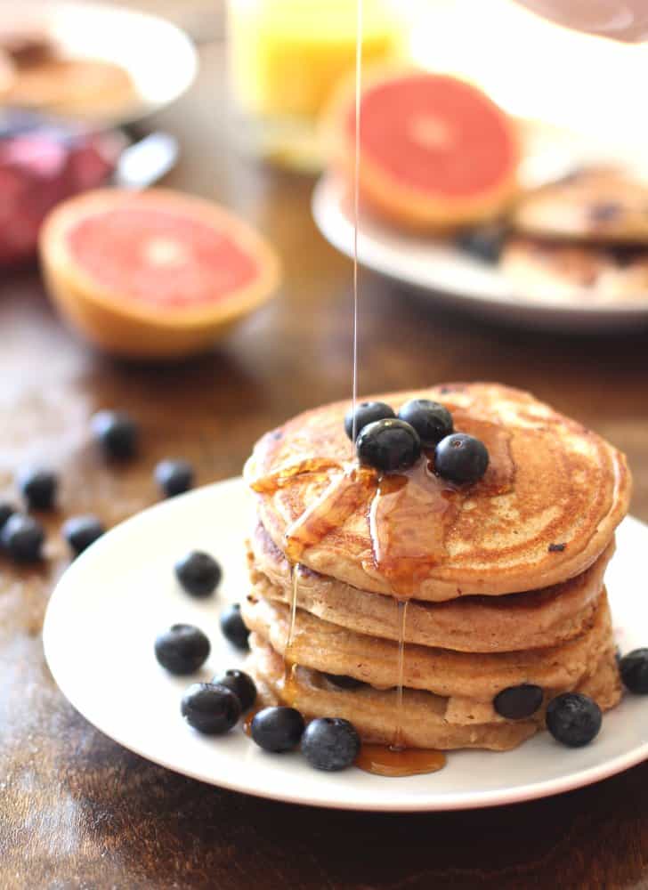 pouring syrup on a stack of pancakes