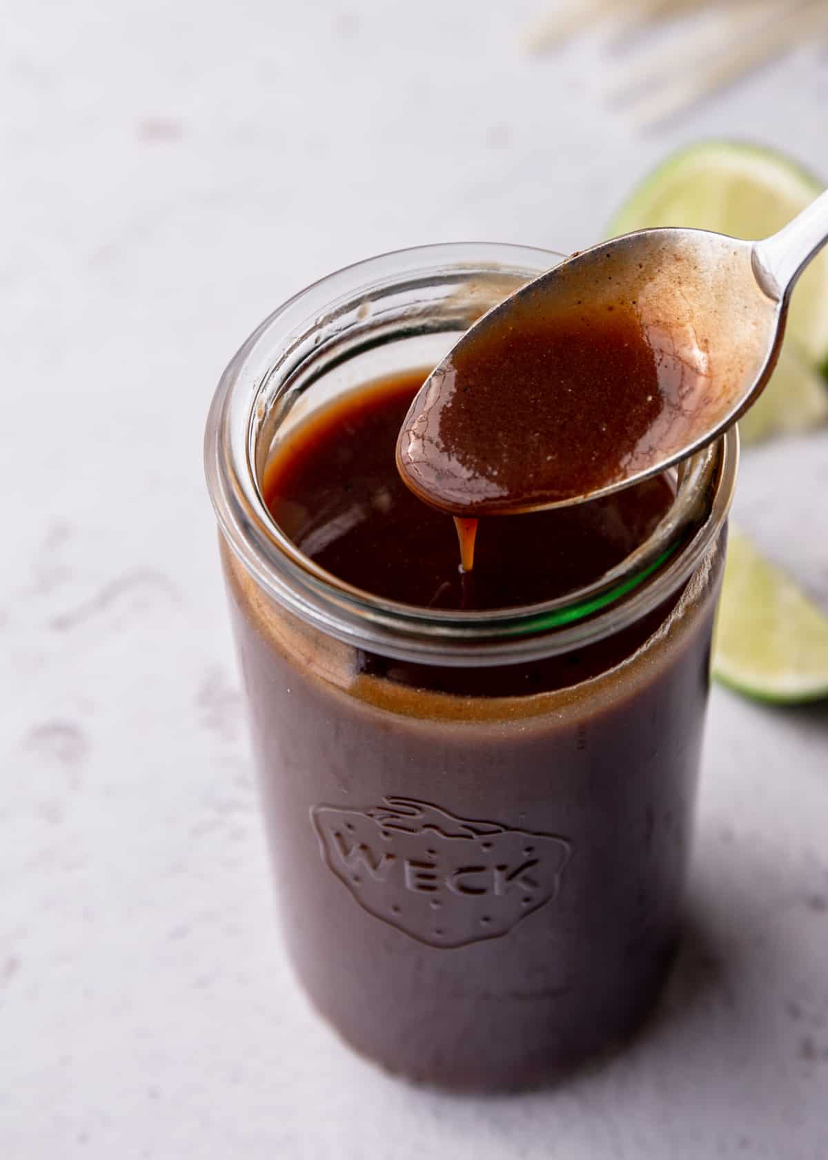 a spoon dipped in a jar of pad thai tamarind sauce
