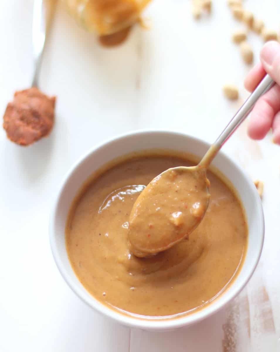 overhead image of a spoon in a ramekin of peanut sauce