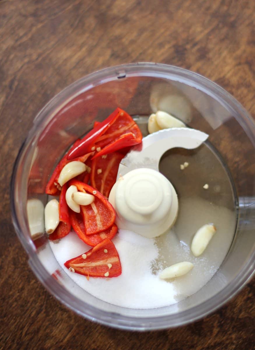 overhead image of garlic and chili peppers in a food processor 