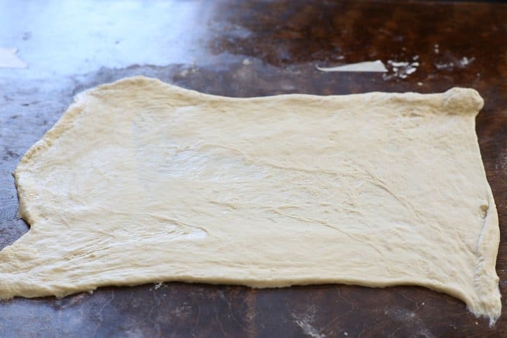 raw pizza dough spread out on a countertop