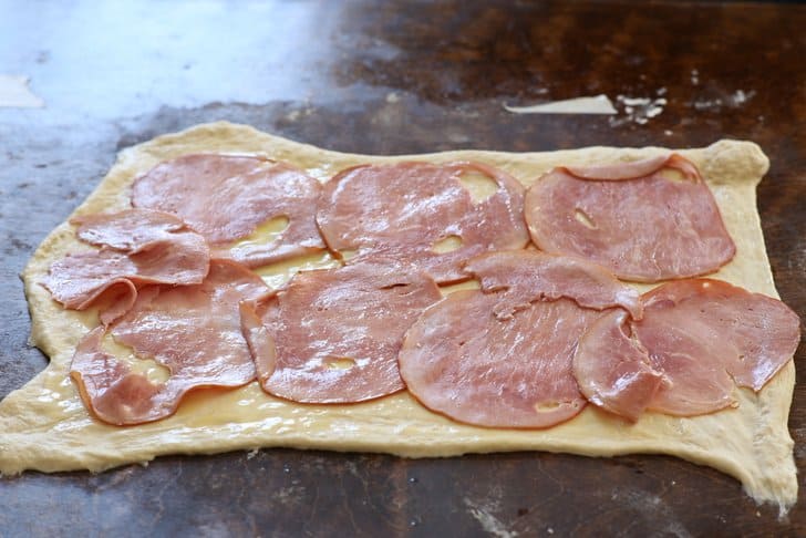 ham slices on raw pizza dough