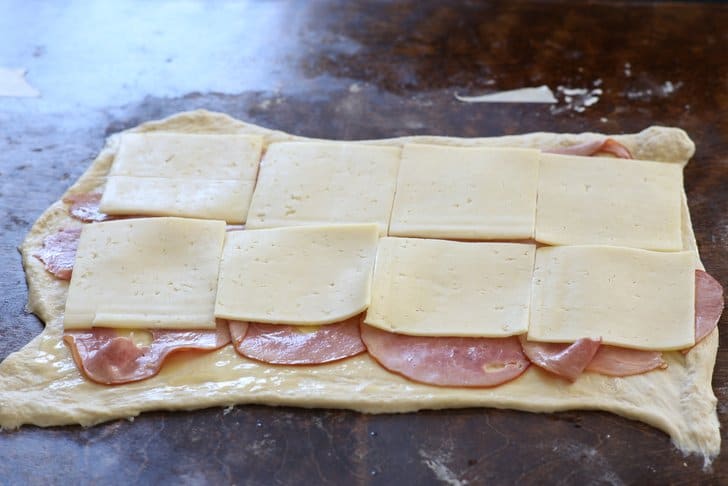 ham and cheese slices on raw pizza dough