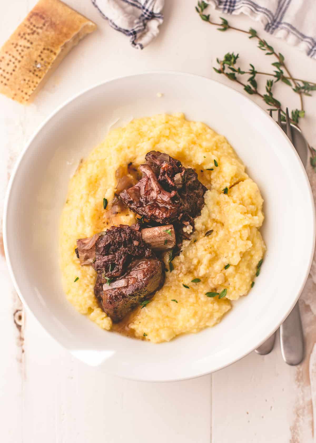 overhead image of short ribs over polenta in a white bowl