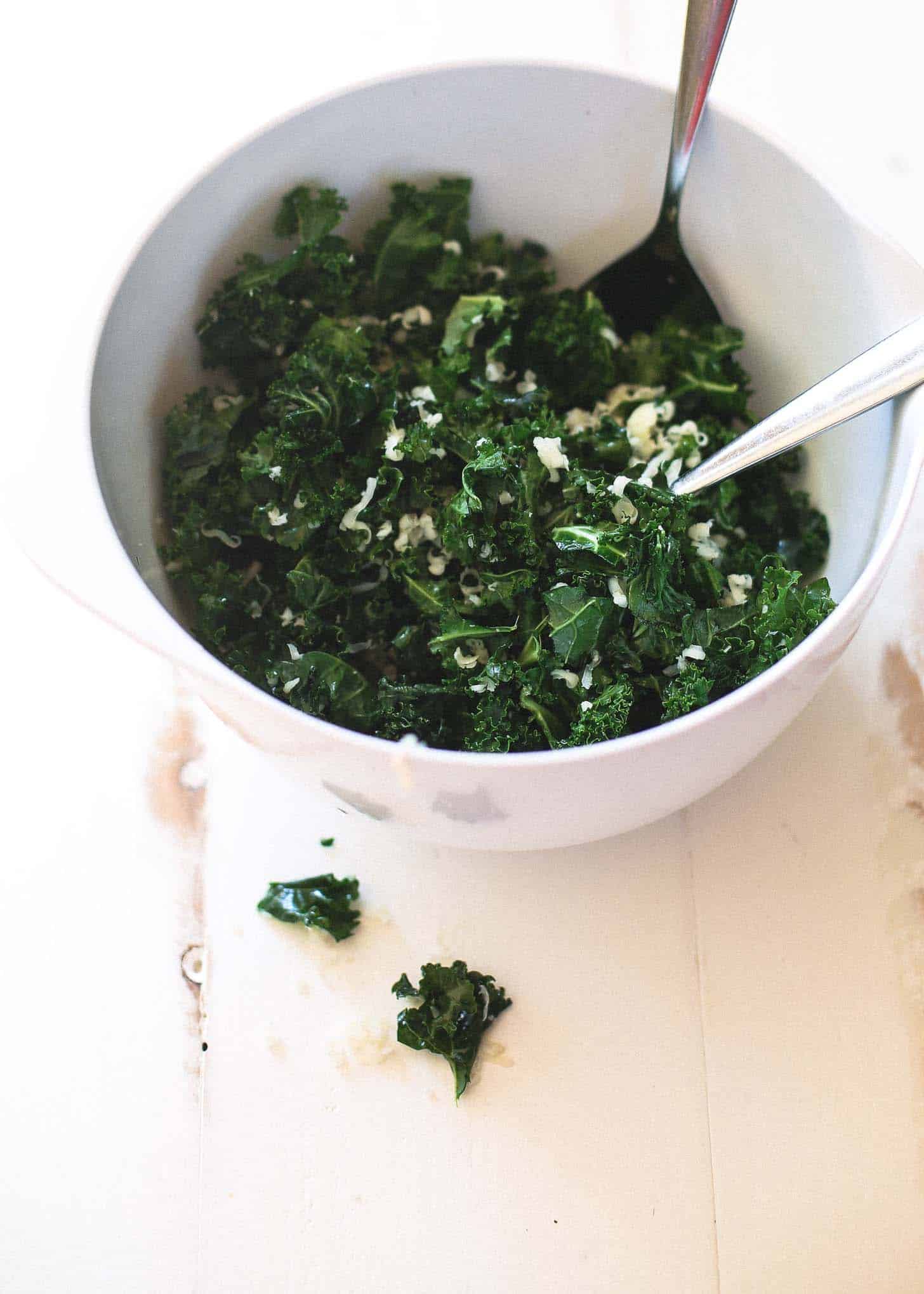 mixing kale in a white bowl