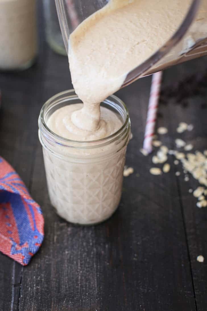 pouring Peanut Butter Chocolate Oat Smoothie from a blender to a glass jar