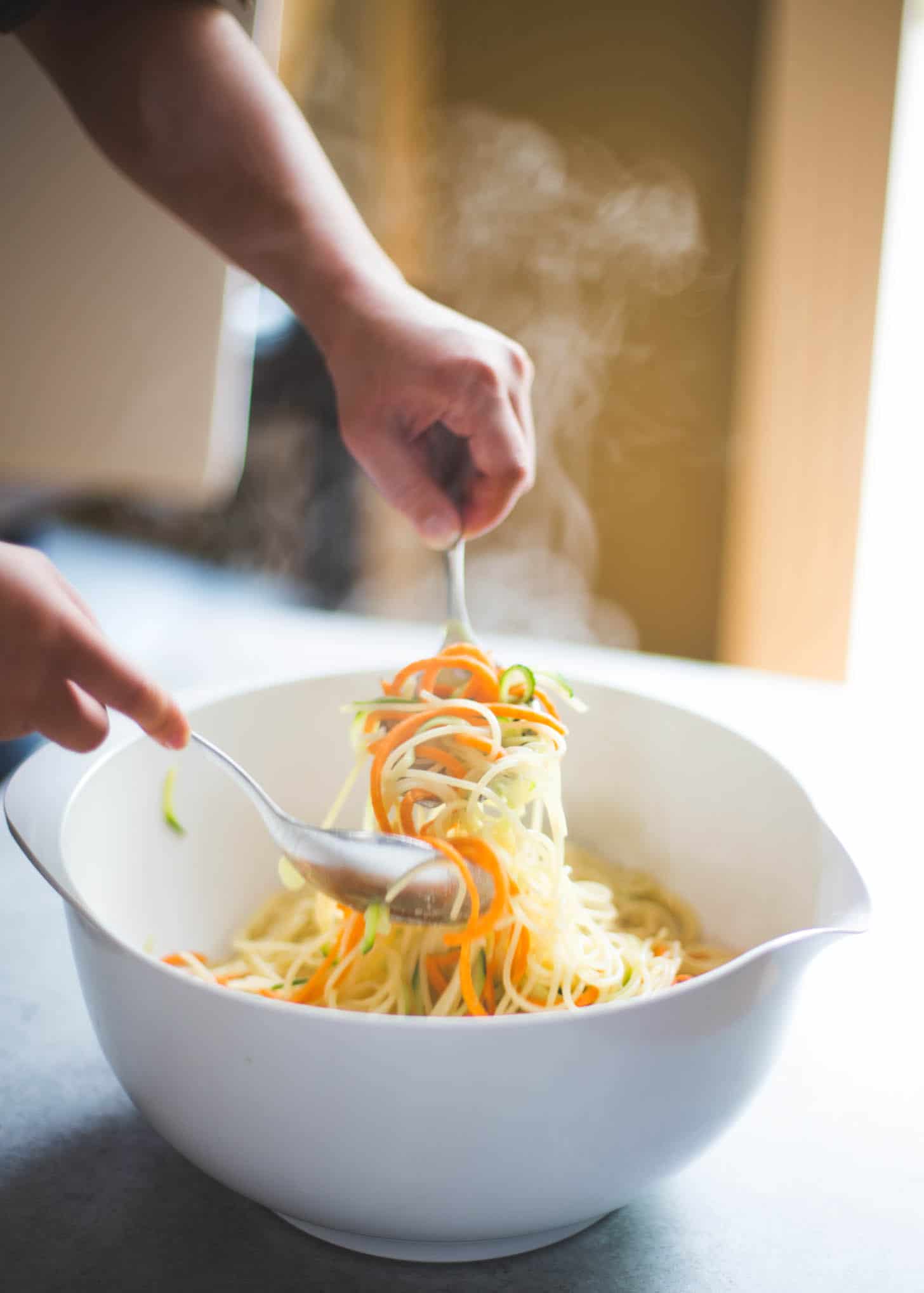 cooked zucchini and sweet potato zoodles in a white bowl