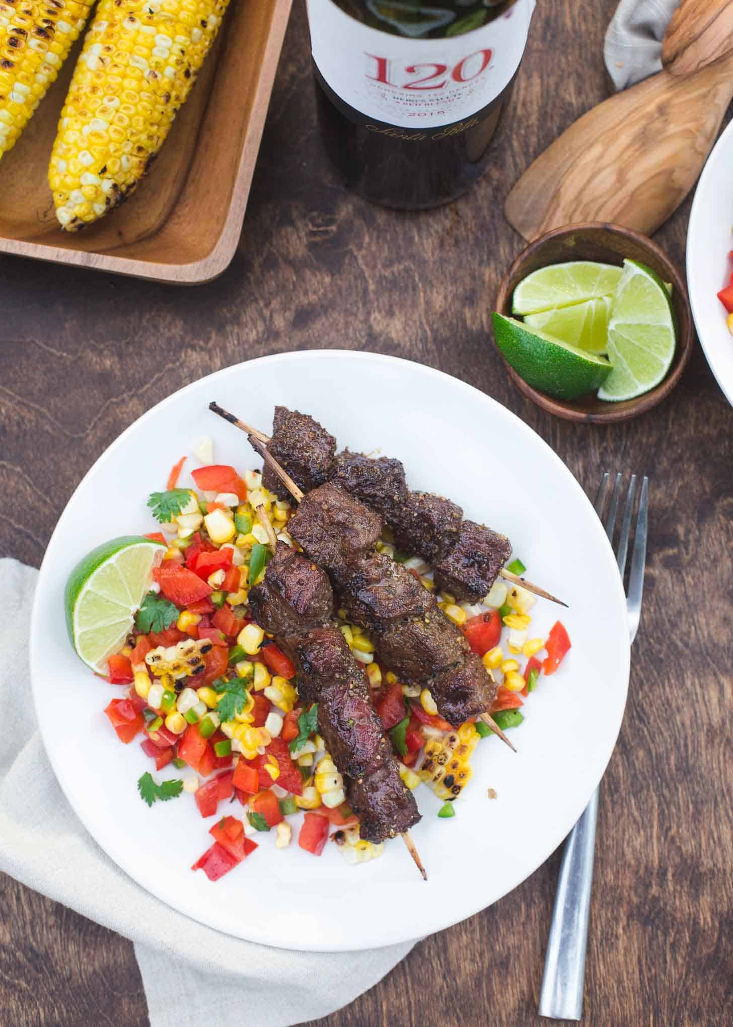 Beef Skewers over Charred Corn Salsa on a white plate