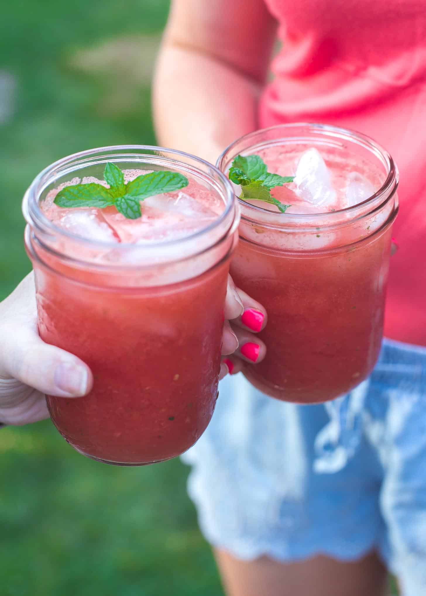 2 women's hands holding jars with watermelon lime cooler