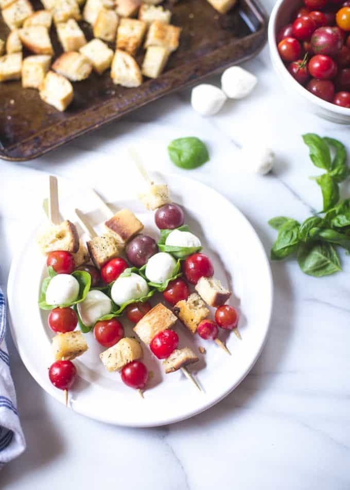 Panzanella Salad Skewers on a white plate on a white table