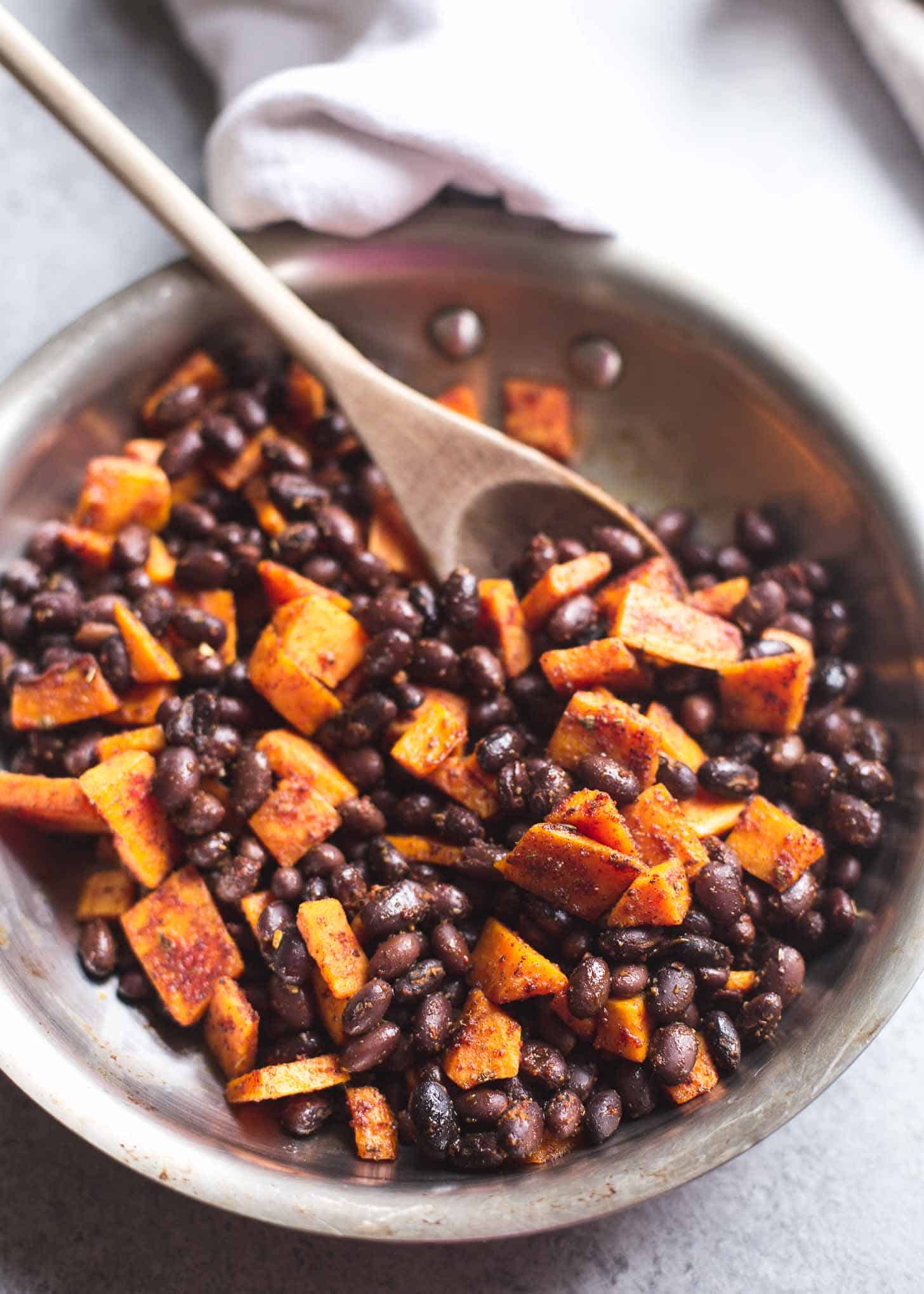 cooking sweet potatoes and black beans in a skillet