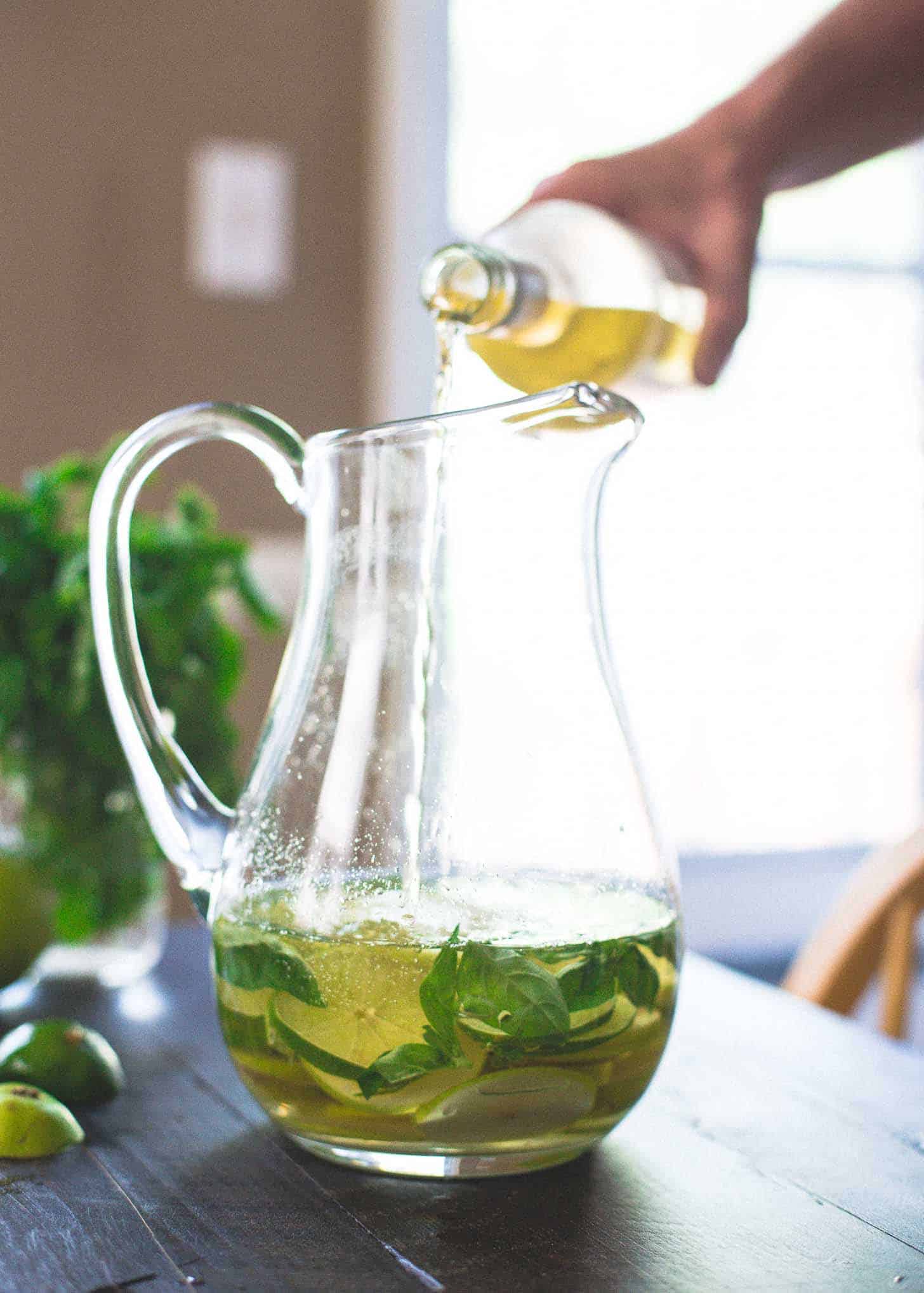 Adding white wine to a Pitcher of Pear and Lime Sangria
