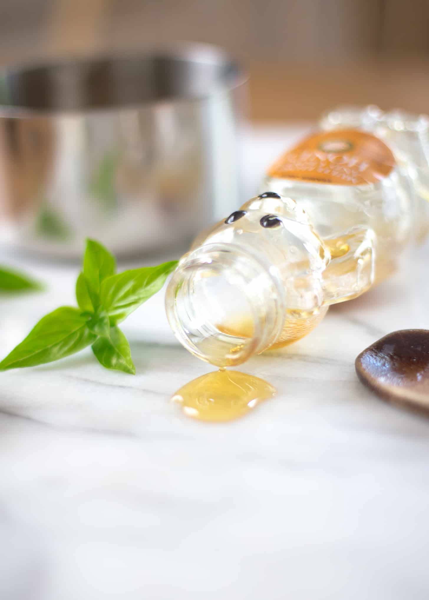 honey and basil leaves on a white table