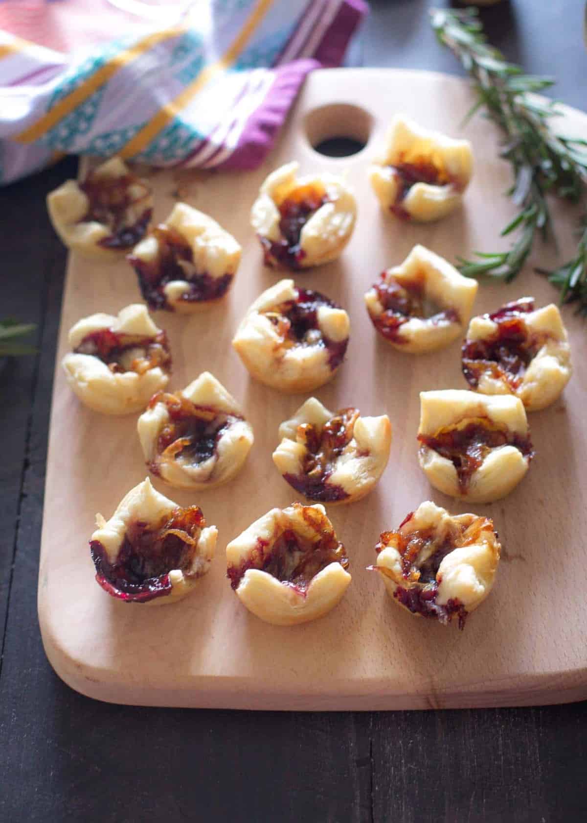 Savory Pastry Bites with Caramelized Onions and Gouda on a wooden tray