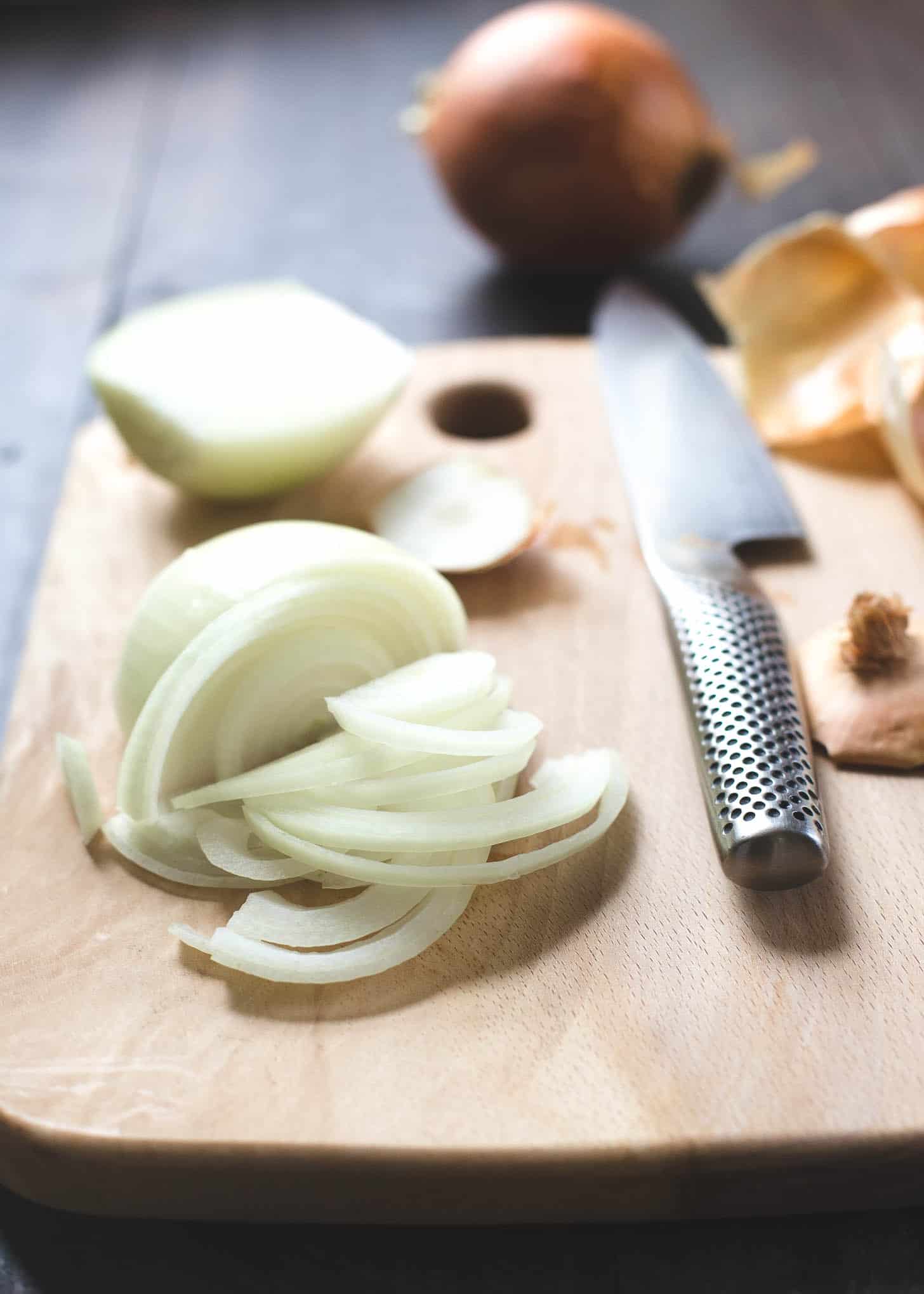 slicing onions on a wooden cutting board