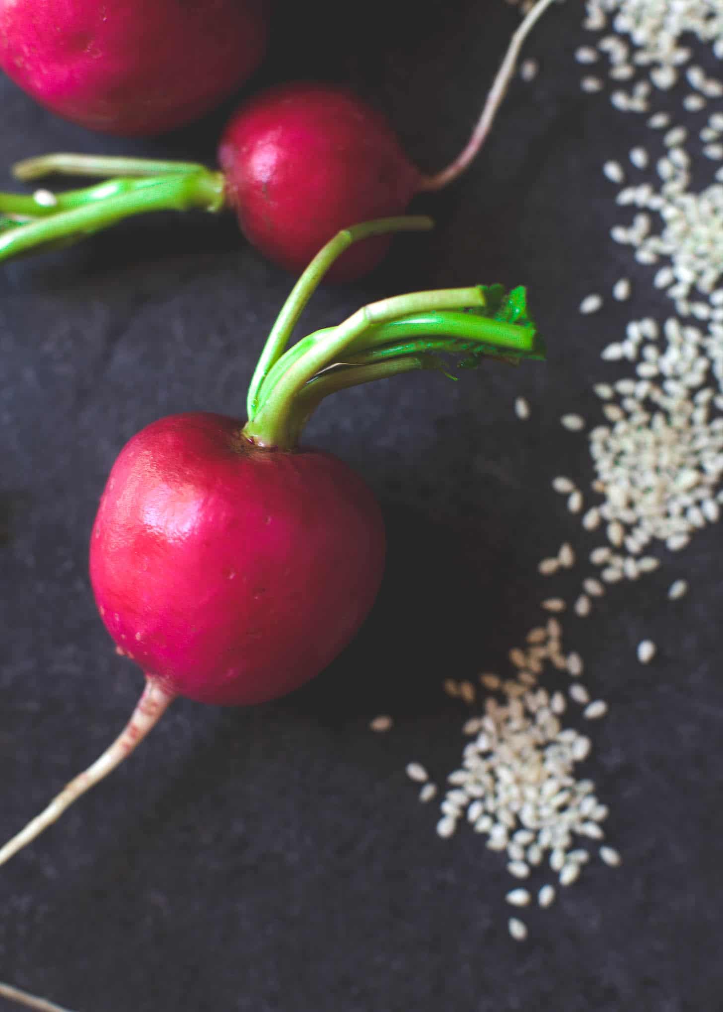 radishes on a grey countertop with sesame seeds
