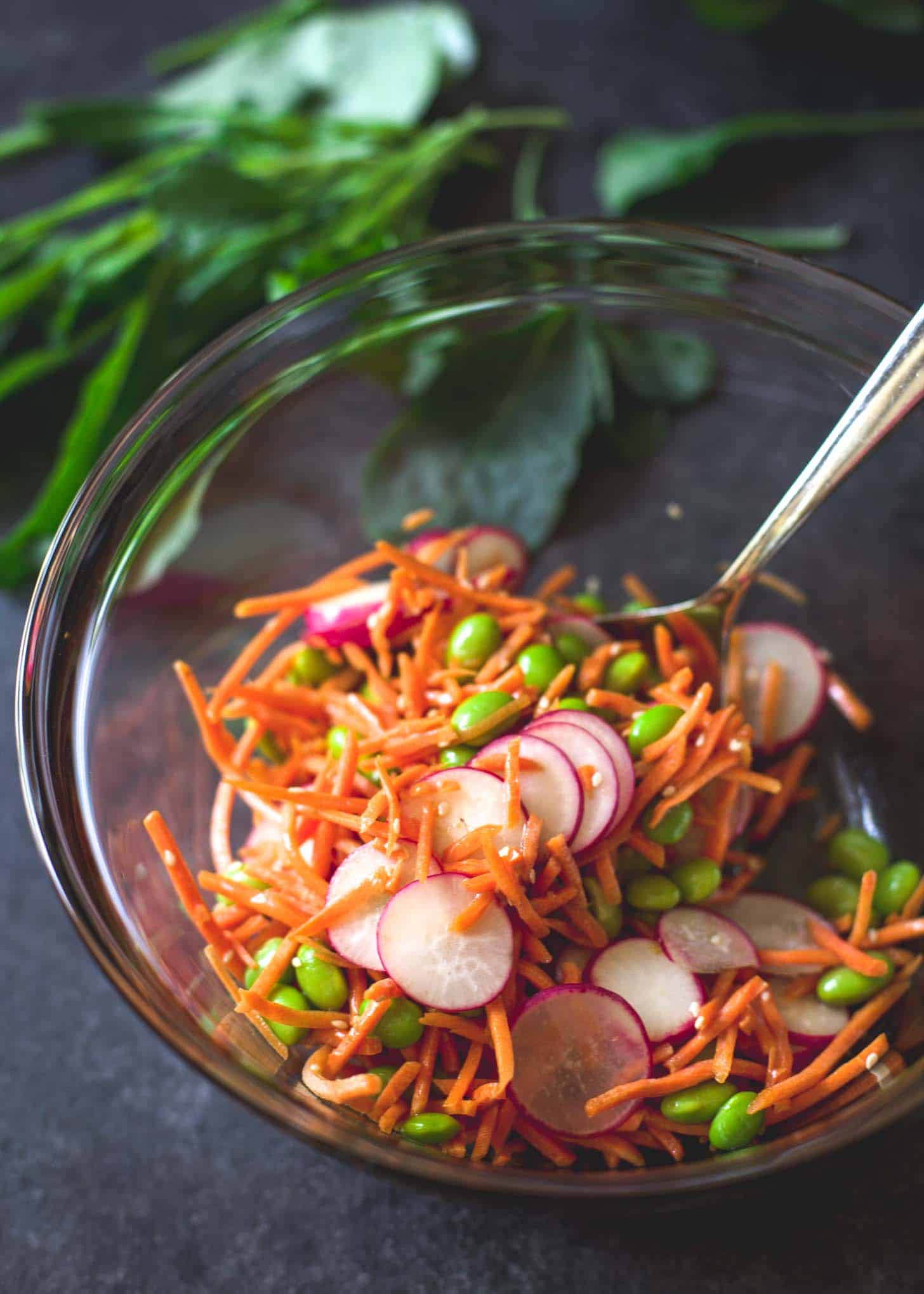 mixing raw vegetables in a clear glass bowl