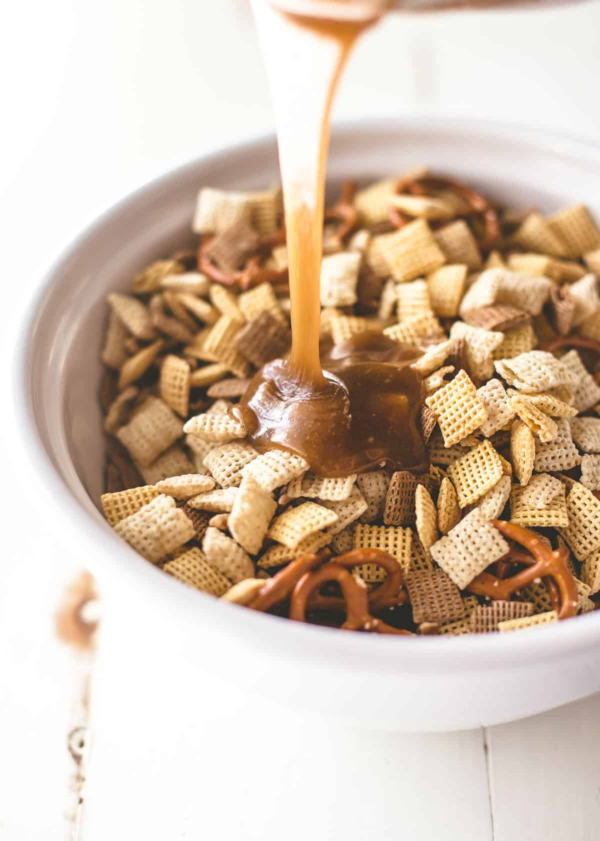 adding syrup to snack mix in a white bowl