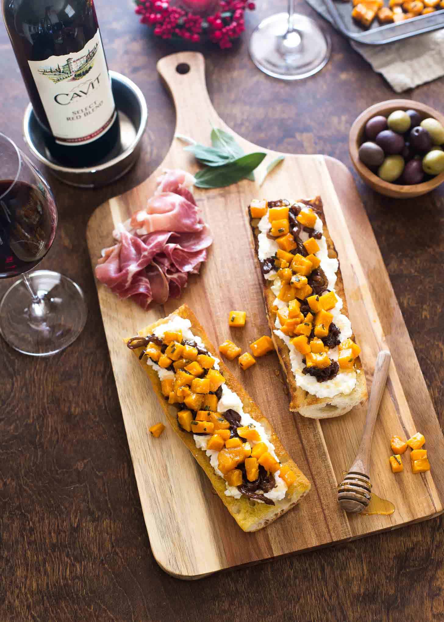 Butternut Squash Crostini on a wooden tray next to a bottle of wine