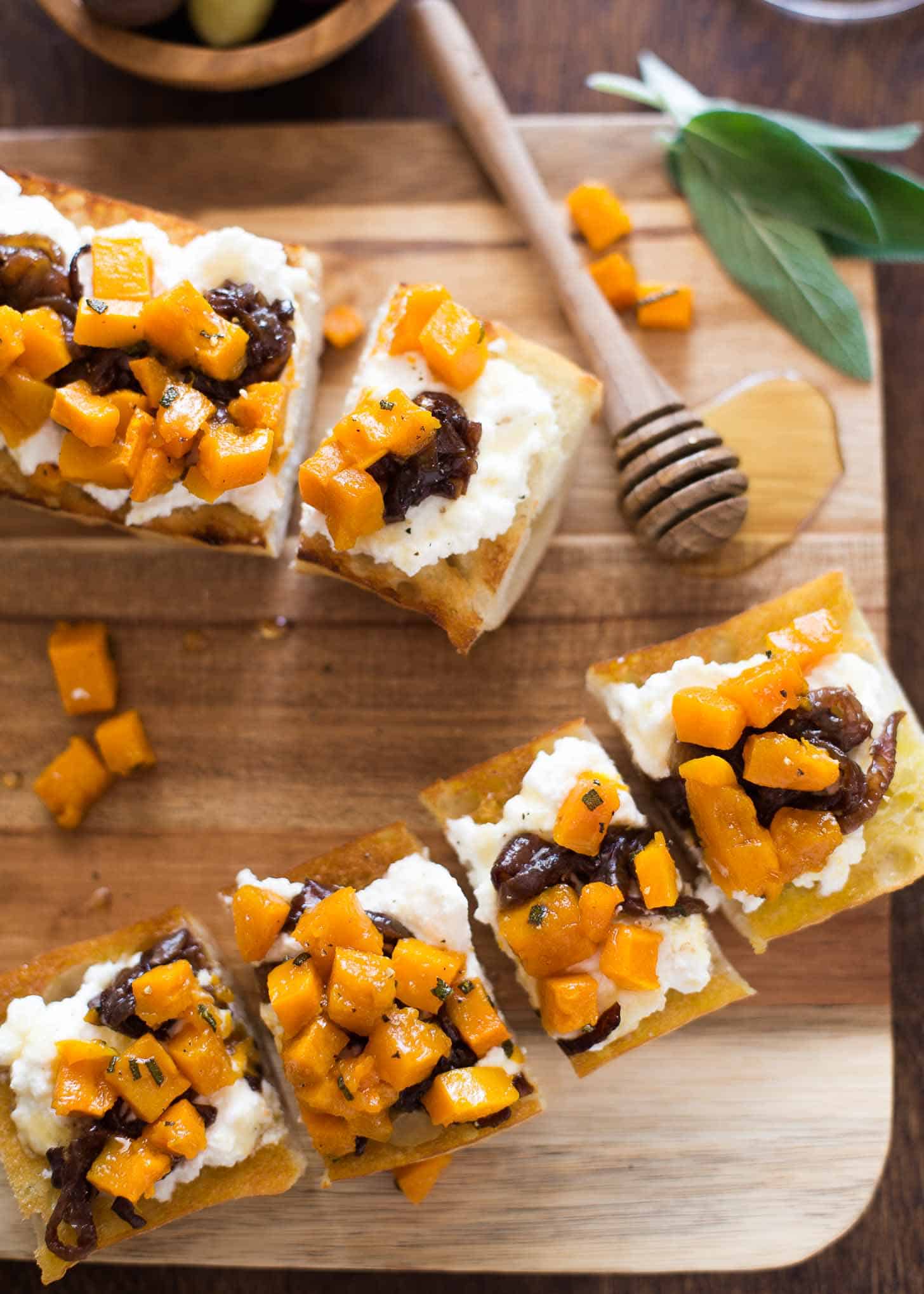 overhead image of Butternut Squash Crostini with Red Wine Caramelized Onions on a wooden cutting board