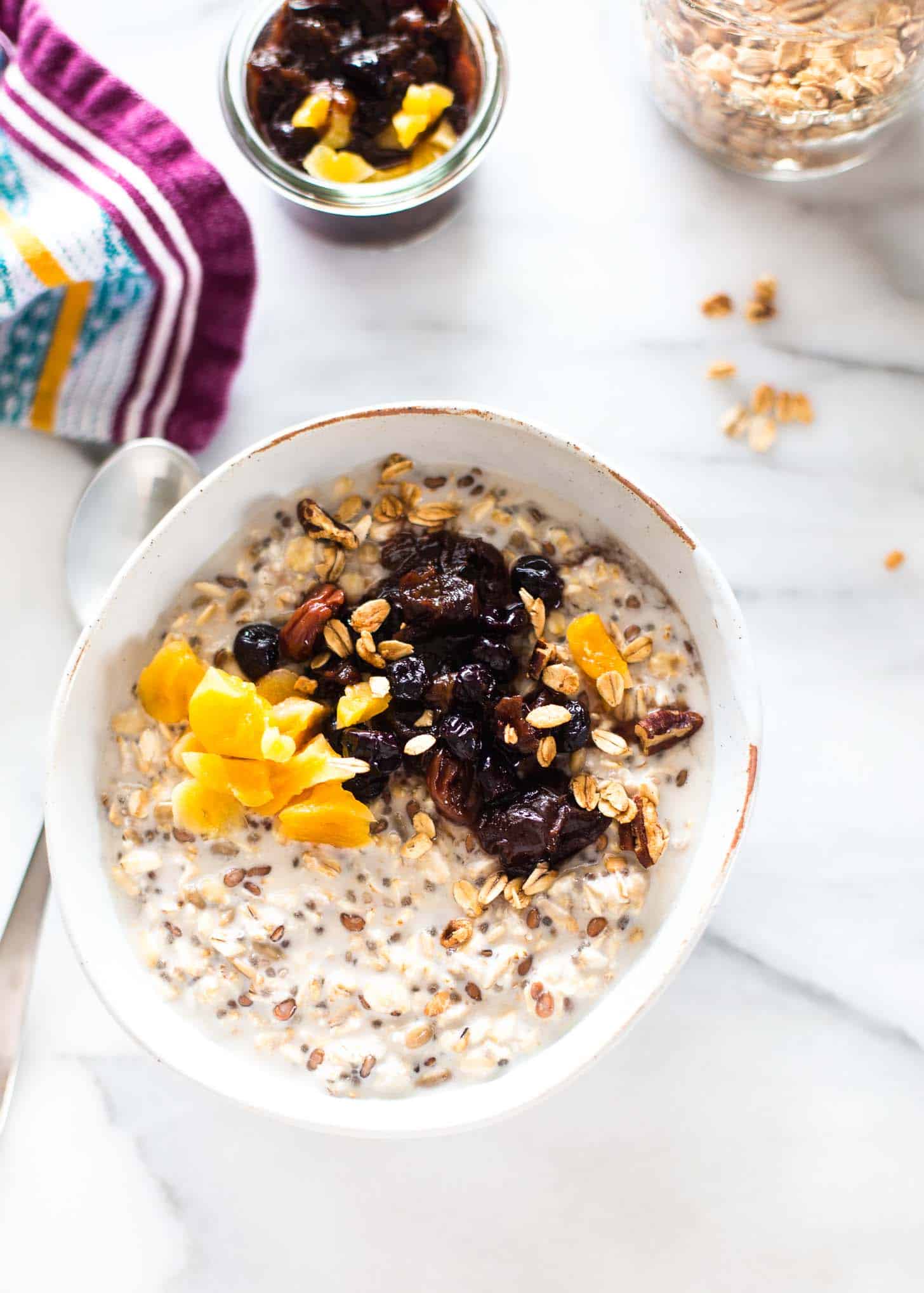 a white bowl of overnight oats topped with fruit