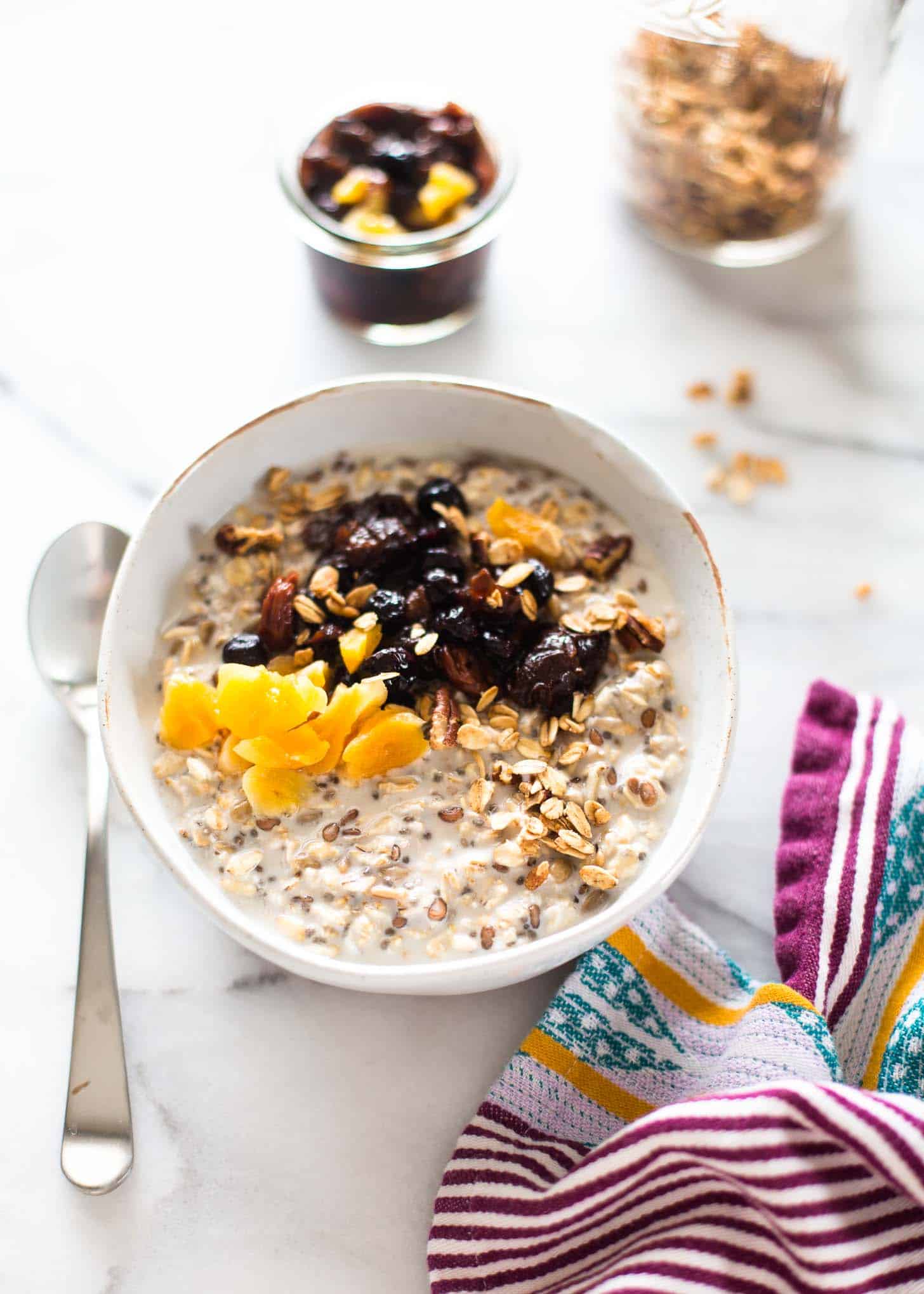 overhead image of a white bowl of overnight oats topped with fruit