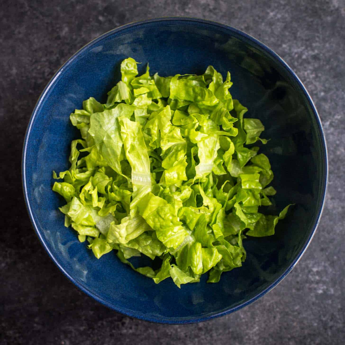 overhead image of chopped lettuce in a blue bowl