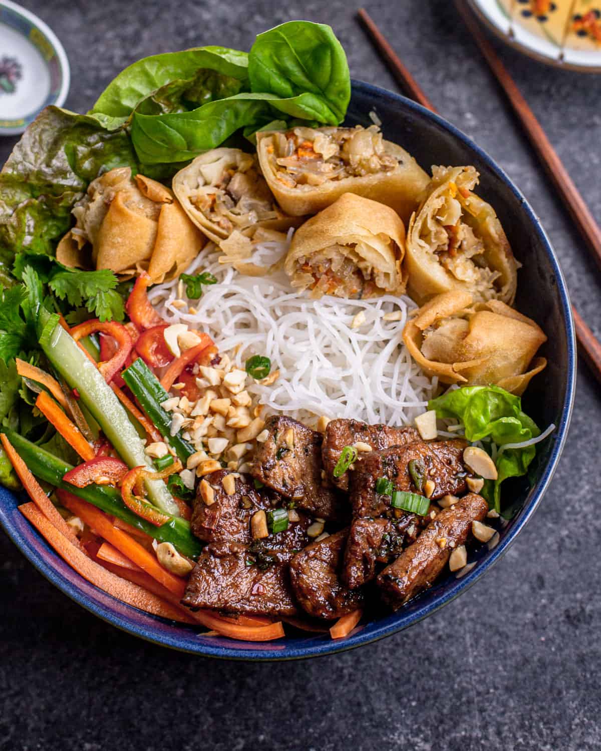 side image of vietnamese noodle bowls in blue bowl with seared strips of lemongrass pork