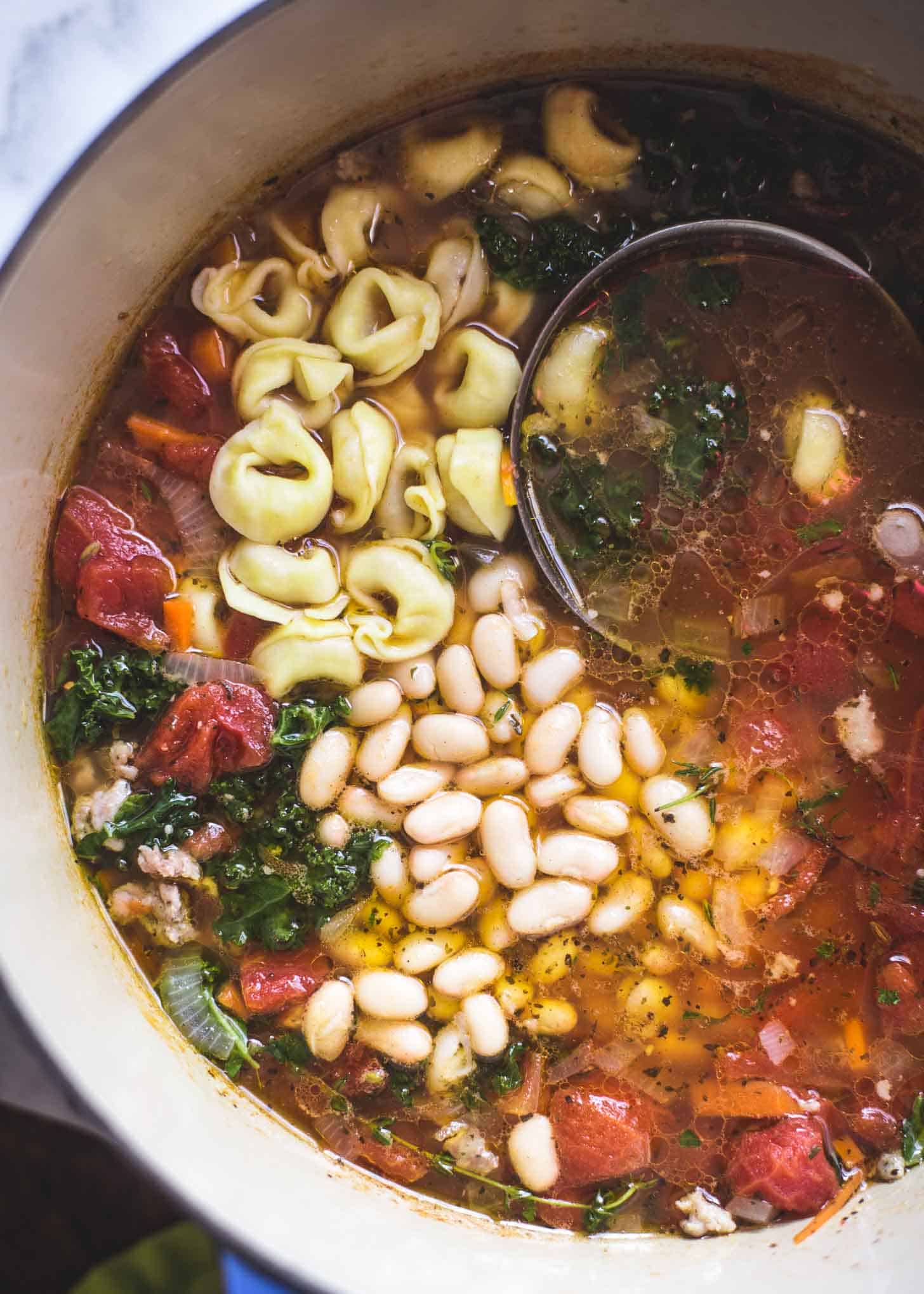 Italian Sausage Soup in a dutch oven with a ladle