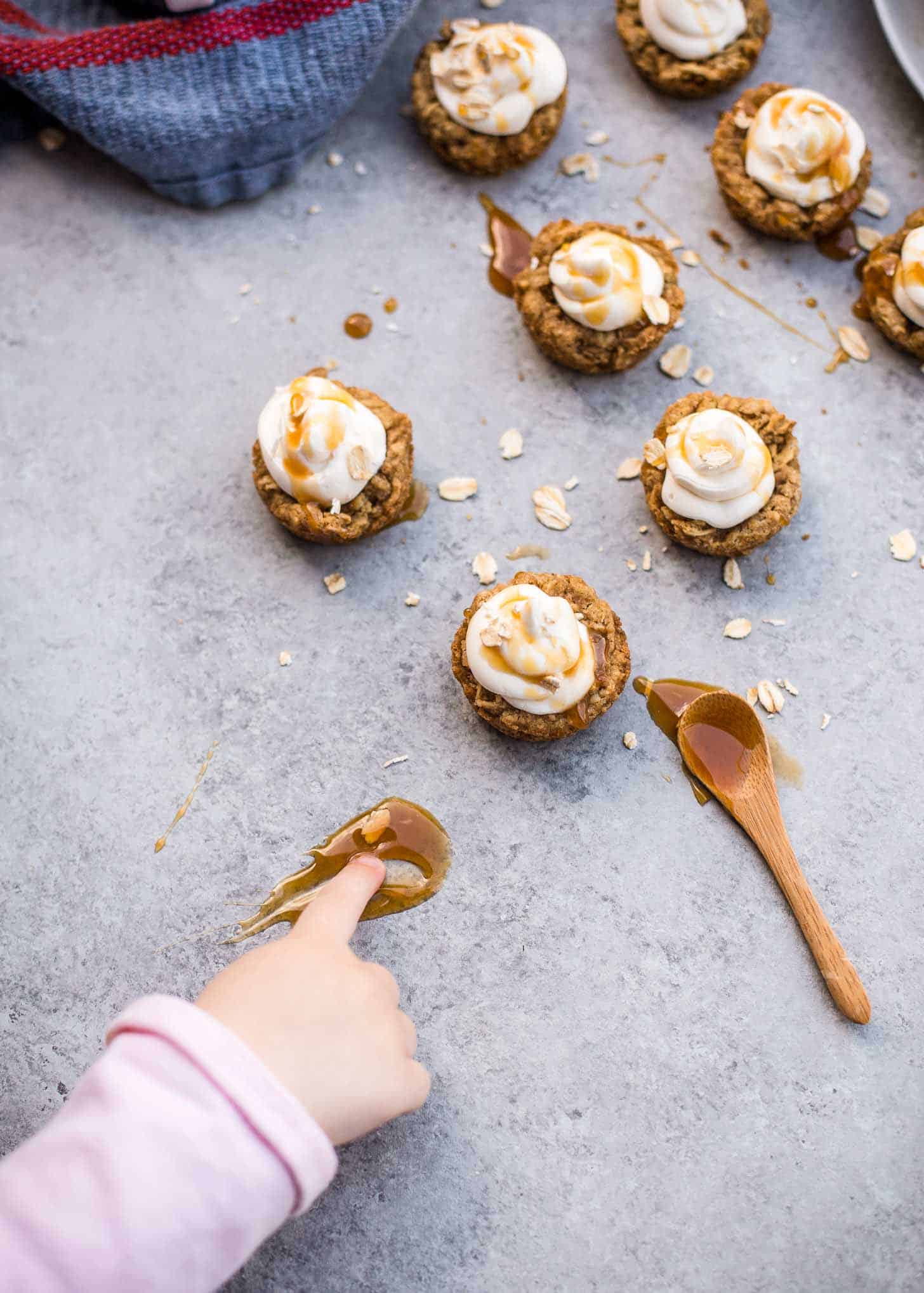 a child's hand reaching for caramel syrup on a table