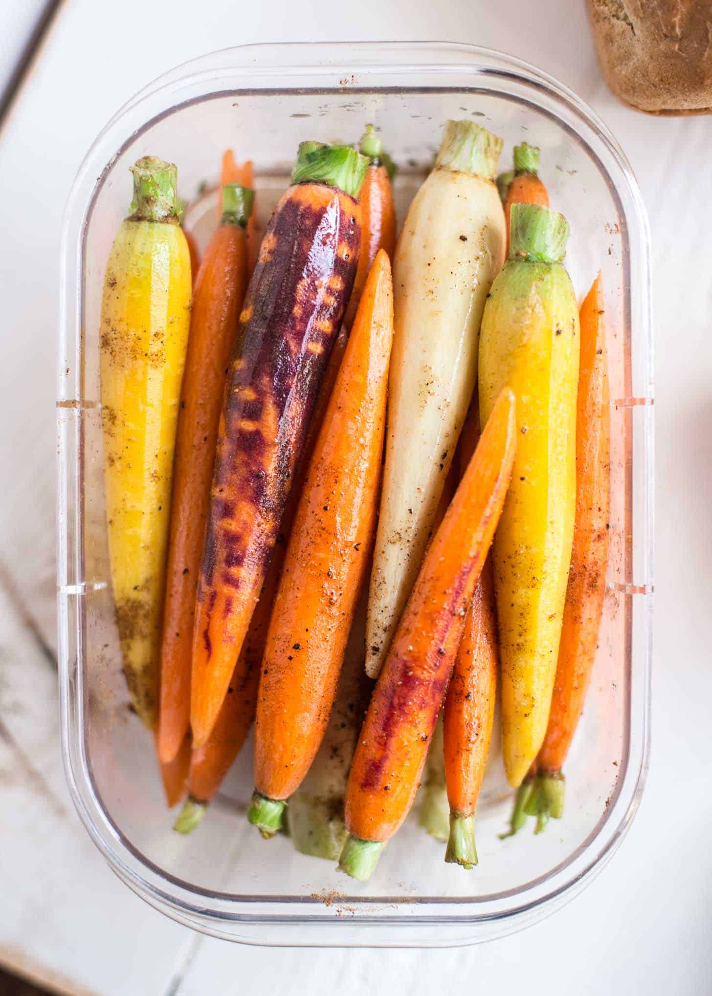 cooked whole carrots in a plastic container