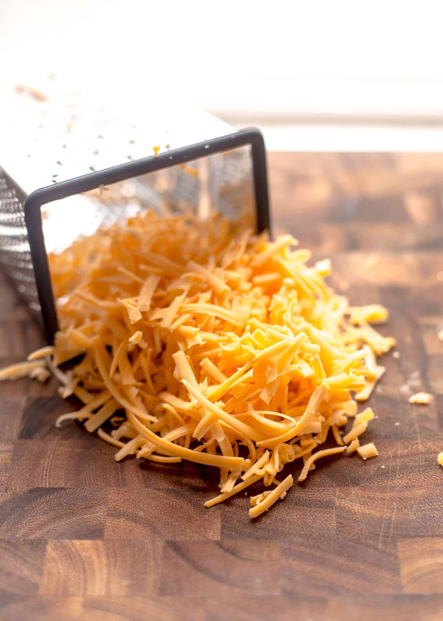 grated cheddar on a wooden butcher block