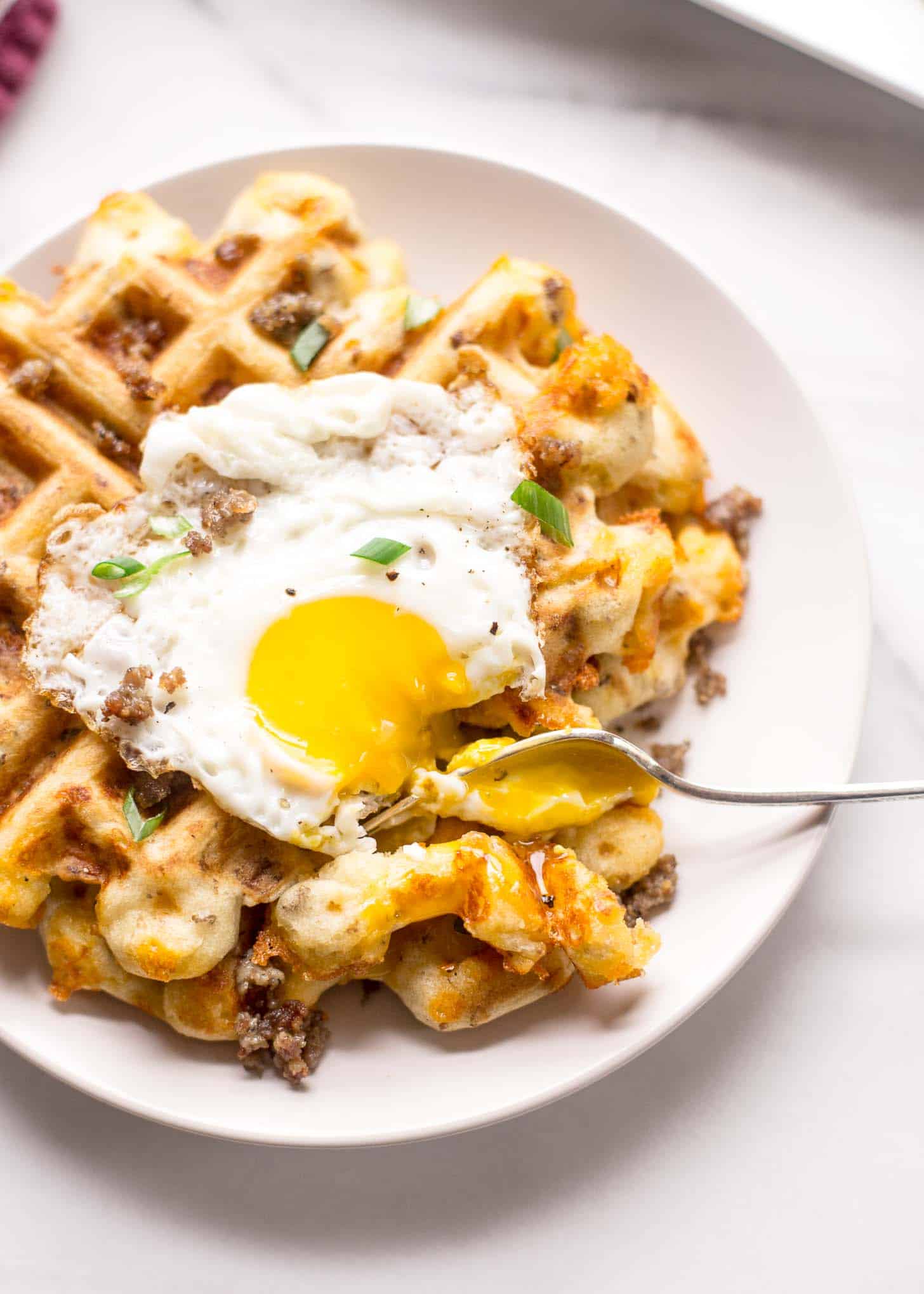 savory waffle, topped with a fried egg on a white plate